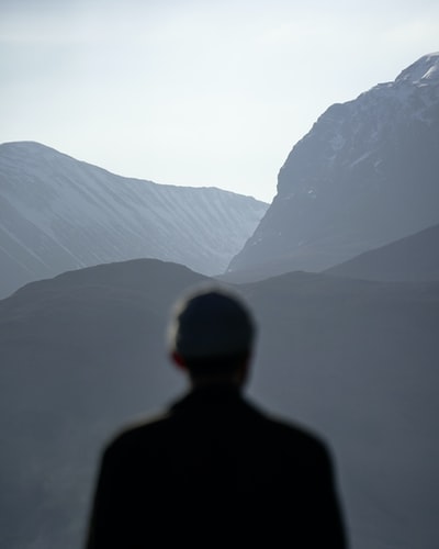黑夹克男子站在山的白天
